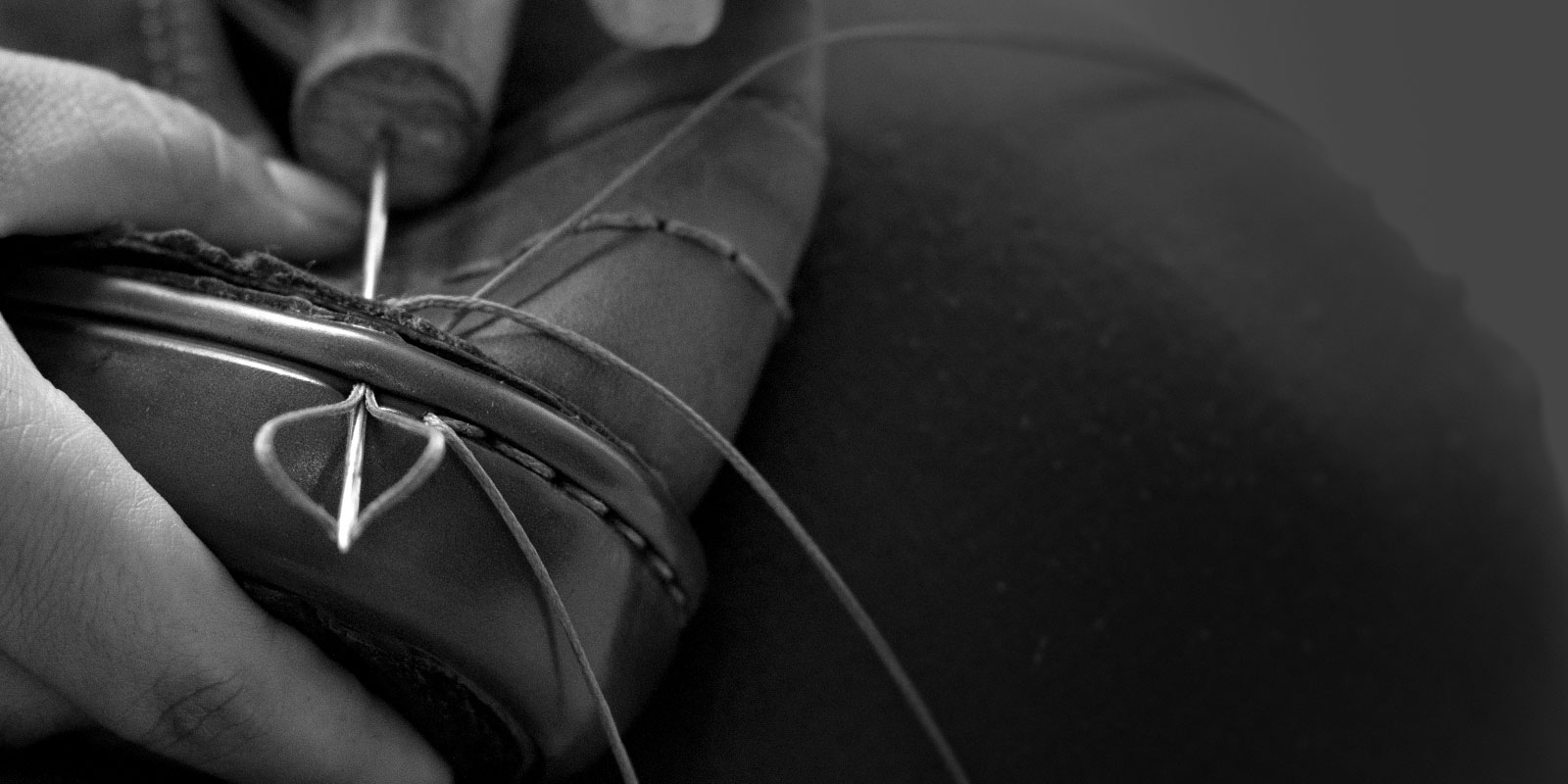 Worker hand-sewing the upper of a shoe to the sole.