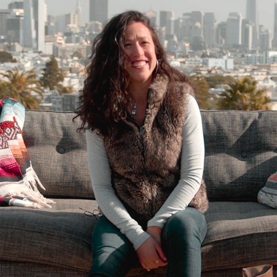 Woman sitting on a couch with a city skyline behind her.